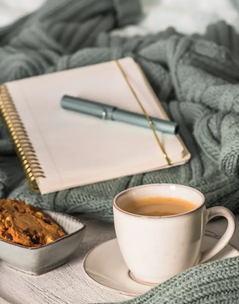 Cup of coffee and cookie on cozy bed. Warm wool sweater for a cozy autumn weekend, breakfast in bed, coffee break. Hygge concept.